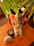 A small statue a candle some rocks and a plant sit on a table to represent healing with feng shui