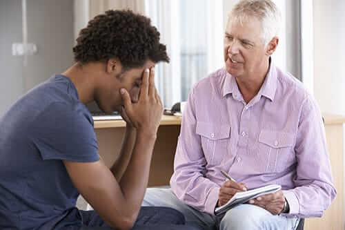 man contemplates inpatient vs outpatient rehab with his doctor